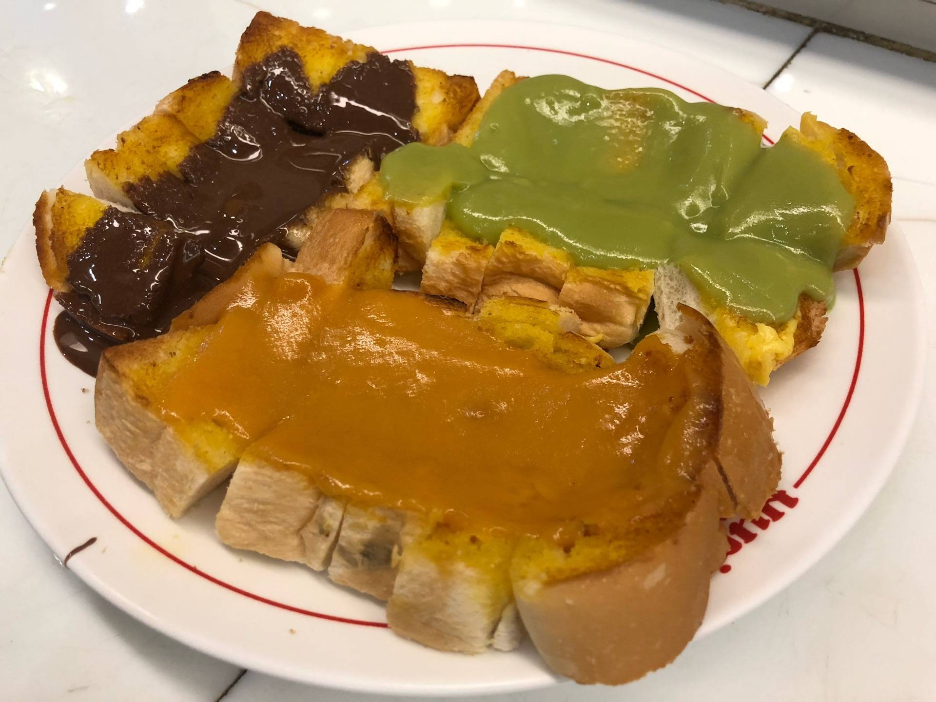 ขนมปังปิ้งหน้าสังขยา ช็อกโกแลต และใบเตยบนจานลายร้านมนต์ นมสด