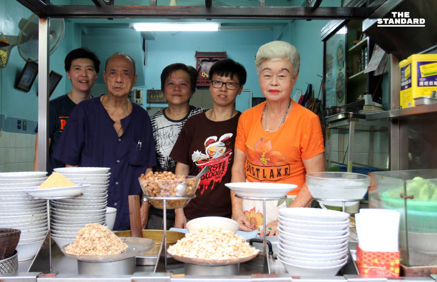 เจ้าของร้านเซี่ยงกี่ ข้าวต้มปลา คุณยายและครอบครัวยืนหน้าเคาน์เตอร์เครื่องข้าวต้ม ในร้านห้องแถวย่านเยาวราช