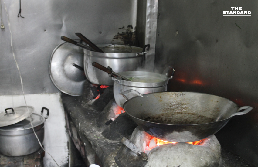 เตาถ่านก่อไฟแดงกับหม้อต้มน้ำซุปสเตนเลสและกระทะใบใหญ่ จุดเด่นของร้านข้าวต้มปลาเตาถ่านเซี่ยงกี่ เยาวราช