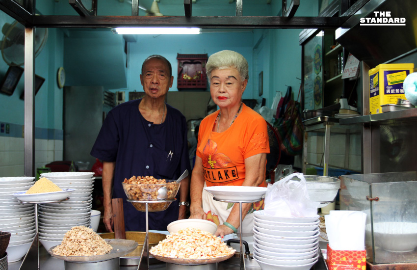 คุณยายเจ้าของร้านเซี่ยงกี่ยืนหลังเคาน์เตอร์ที่วางบะเต็งและเครื่องเคียงข้าวต้มปลา ย่านเยาวราช