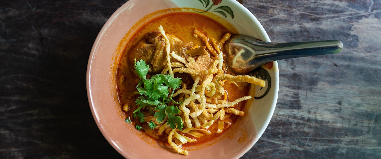 ชามข้าวซอยน้ำแกงข้น โรยบะหมี่ทอดกรอบและผักชี ของร้านเฮือนเพ็ญ เชียงใหม่