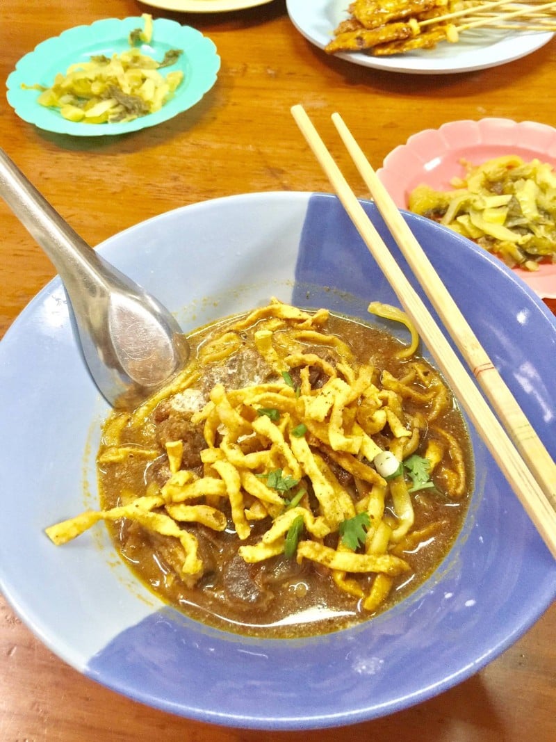 ชามข้าวซอยเนื้อโรยเส้นกรอบ พร้อมผักดองและไม้สะเต๊ะที่ร้านข้าวซอยลำดวน ฟ้าฮ่าม