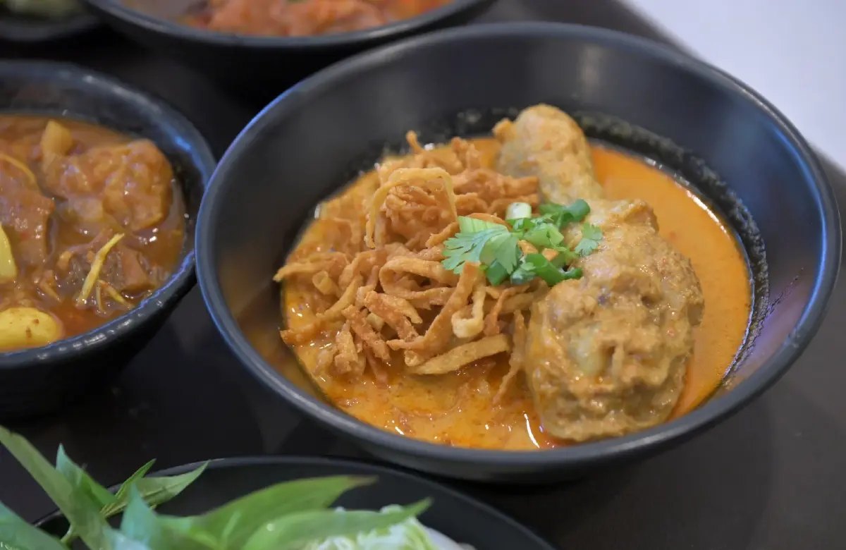 ชามข้าวซอยไก่น้ำแกงข้น โรยบะหมี่ทอดกรอบและผักชี ของร้านข้าวซอยลำดวนฟ้าฮ่าม เชียงใหม่