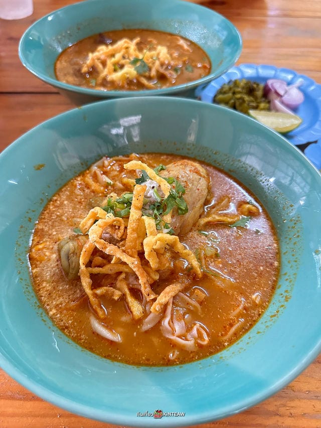 ข้าวซอยไก่ชามสีฟ้าของร้านข้าวซอยลำดวน ฟ้าฮ่าม เชียงใหม่ โรยเส้นทอดกรอบ เสิร์ฟคู่ผักกาดดอง หอมแดง และมะนาว