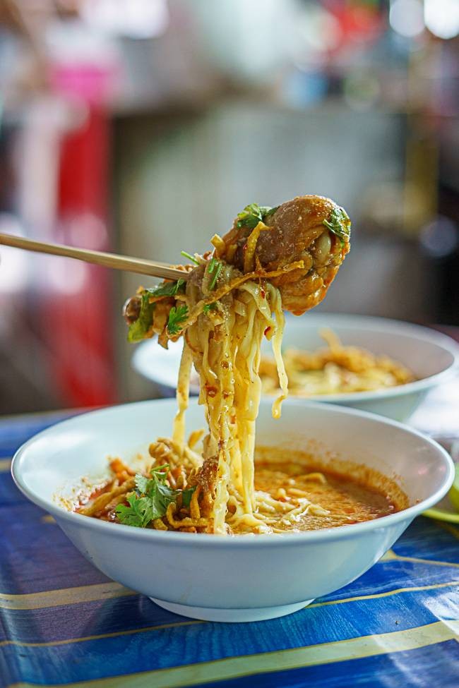 ข้าวซอยเนื้อ คีบเส้นขึ้นจากชาม น้ำแกงข้นเข้มข้น