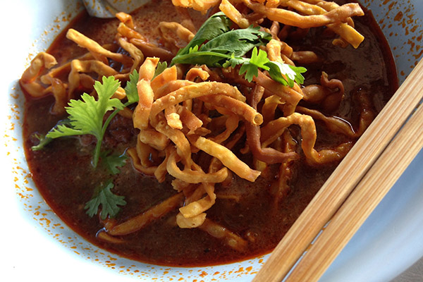 ชามข้าวซอยน้ำข้นของร้านข้าวซอยแม่มณี โรยเส้นกรอบและผักชี