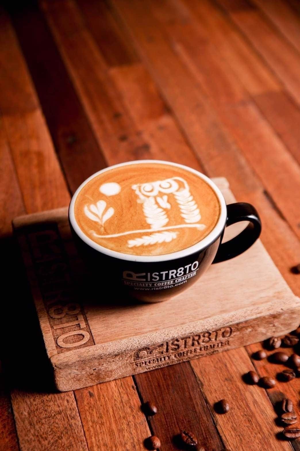 แก้วกาแฟแบรนด์ Ristr8to ลาเต้อาร์ตลายนกฮูกบนแผ่นไม้พร้อมเมล็ดกาแฟ ร้านกาแฟนิมมานเชียงใหม่