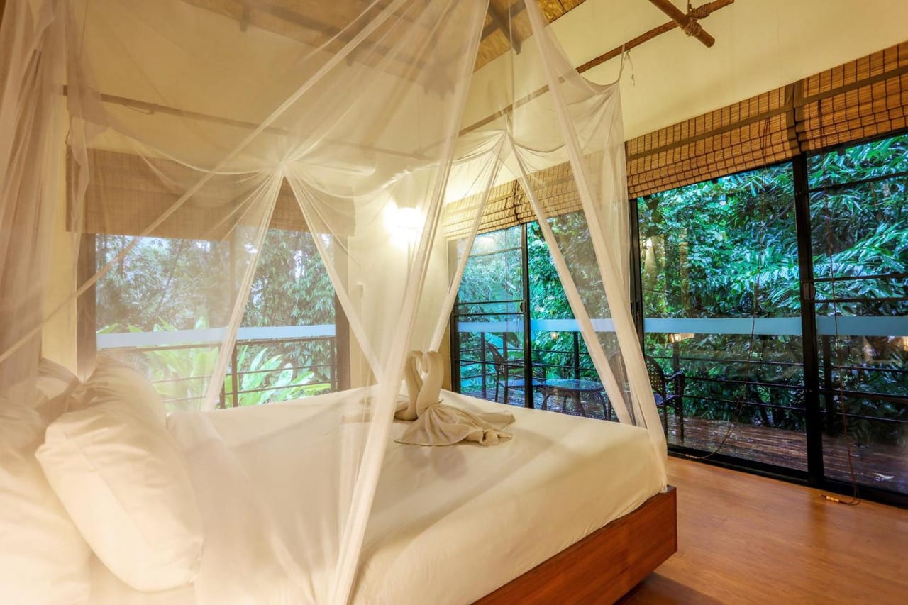 ห้องพัก Deluxe Green Bungalow เตียงคิงมุ้งคลุมและระเบียงรอบมองสวนป่าที่ Anurak Community Lodge