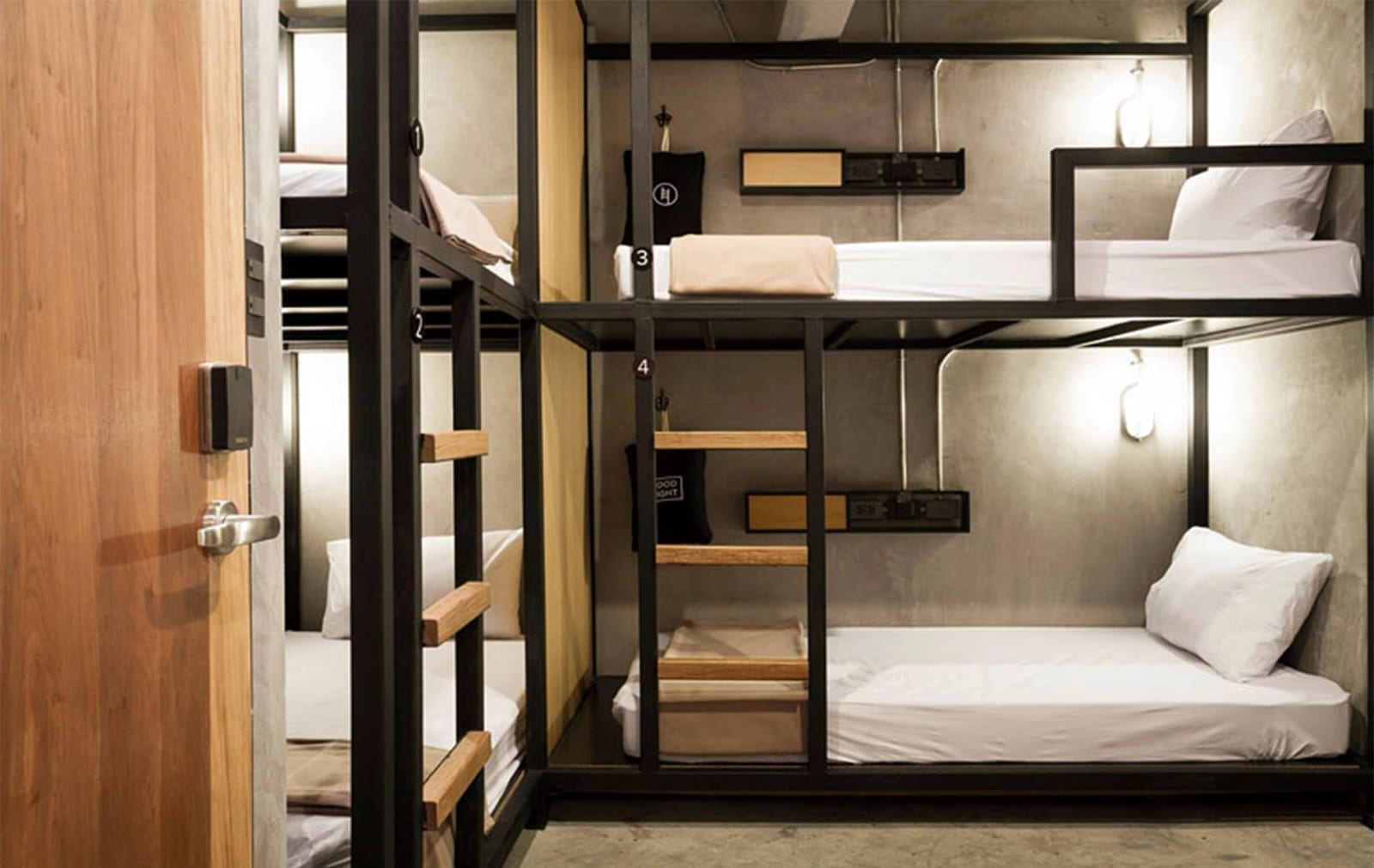 ดอร์มเตียงสองชั้น 4 เตียงของ Bed Station Hostel แต่ละเตียงมีไฟอ่านหนังสือและปลั๊กชาร์จ