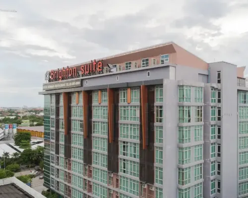 Brighton Suite Bangkok building exterior, grey and teal facade with rooftop signage