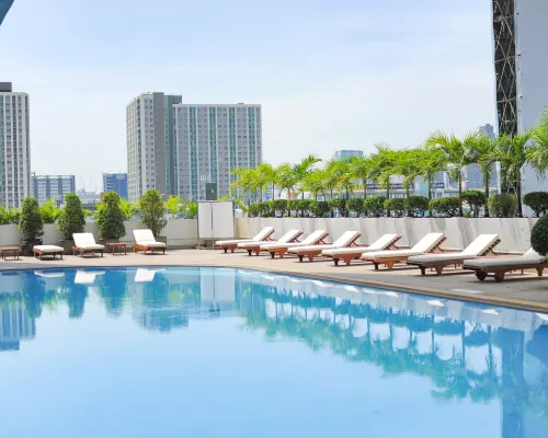 Large outdoor pool at Golden Tulip Sovereign Hotel Bangkok with sun loungers and poolside seating