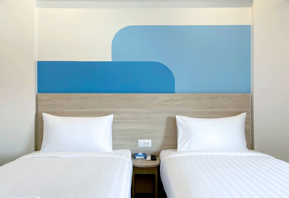 A standard room at Hop Inn Bangkok Onnut Station — clean white bedding, strong air conditioning