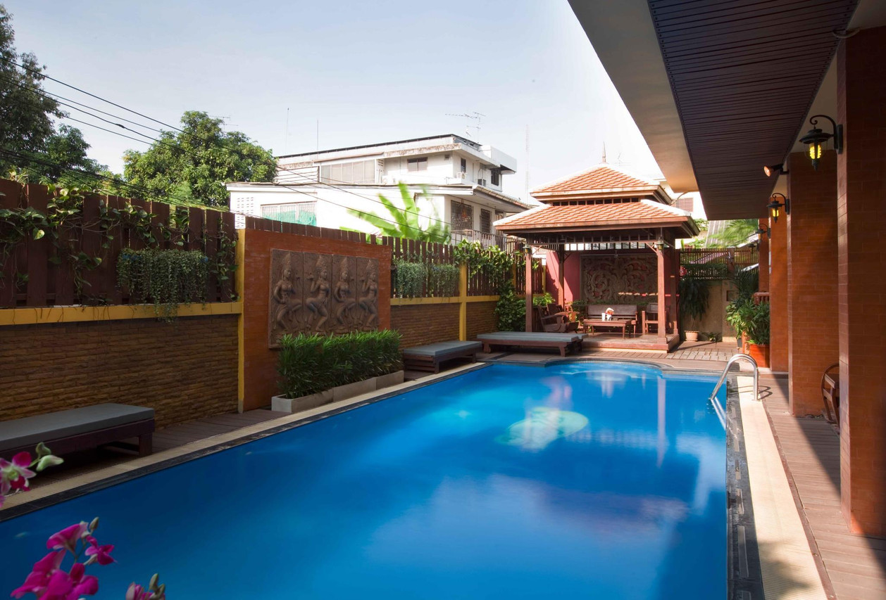 สระว่ายน้ำกลางแจ้งของ Lamphu Tree House ล้อมรอบด้วยสวนและร่มไม้