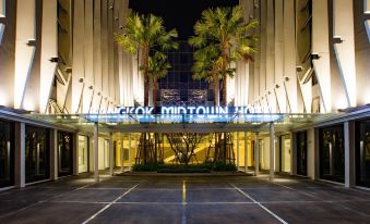 Bangkok Midtown Hotel guest room — warm-toned interior, large clean bed, flat-screen TV and minibar