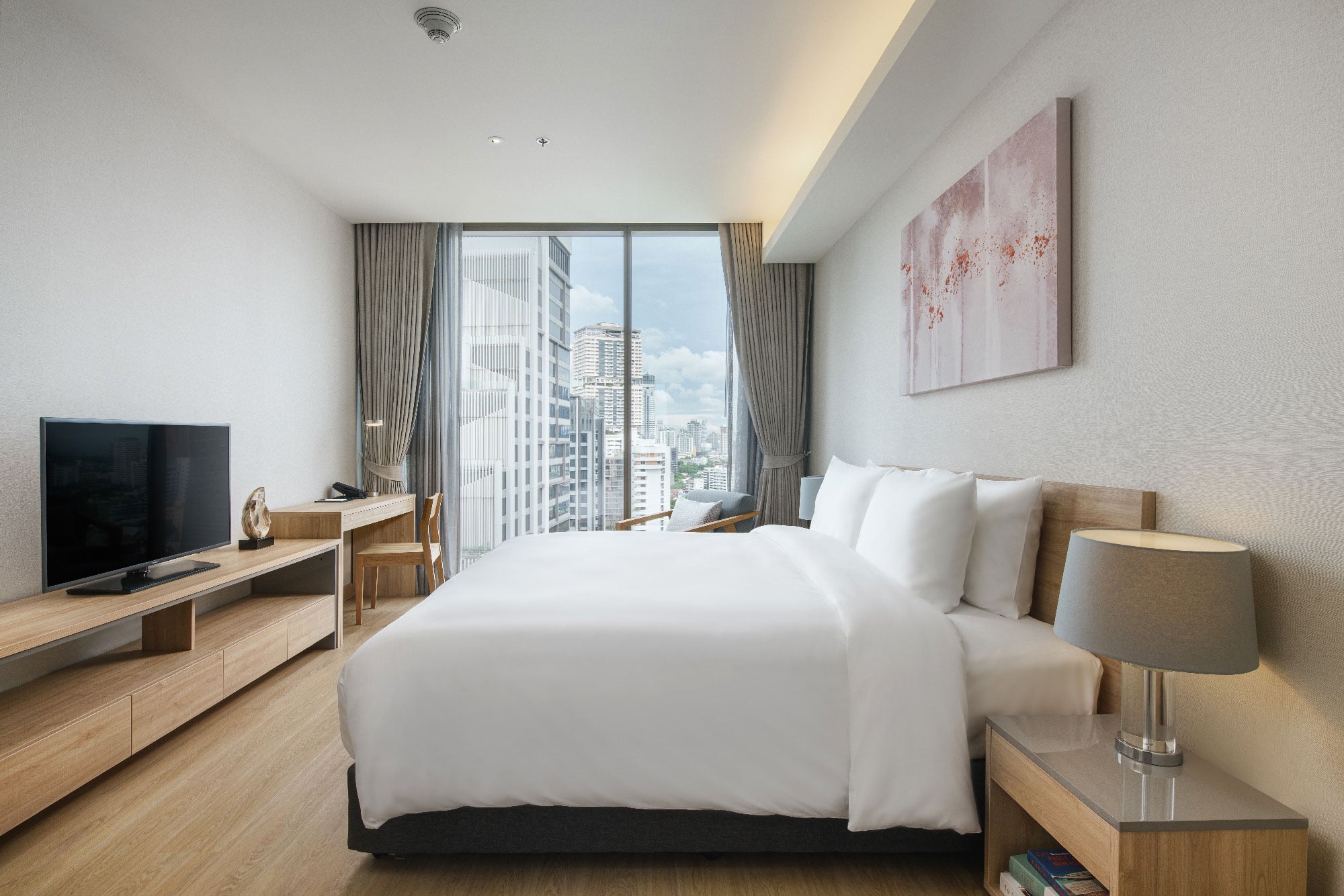 ห้อง One-Bedroom Deluxe ของ Oakwood Suites Bangkok เตียง King Size ตกแต่งสะอาด มีโต๊ะทำงาน