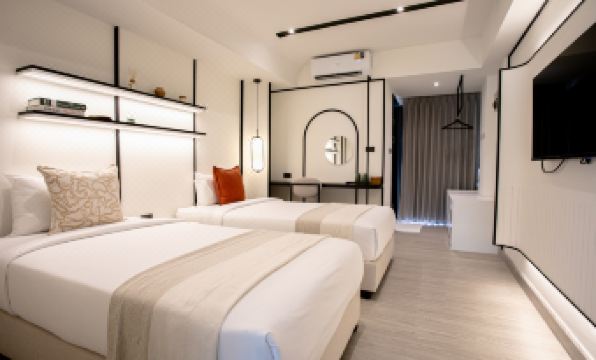 ล็อบบี้โอ่อ่าของ Pillow B Hotel มองเห็นโซฟาสีขาวและโคมไฟทองแดงจากมุมฝั่งรับเรค