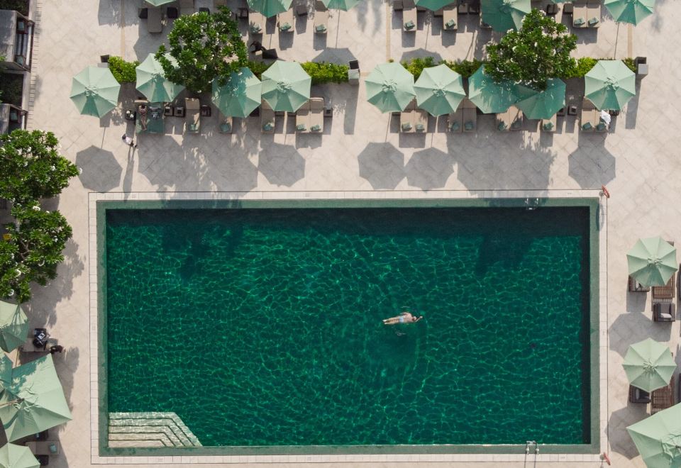 The Sukhothai Bangkok's large outdoor pool surrounded by tropical gardens and Thai pavilions