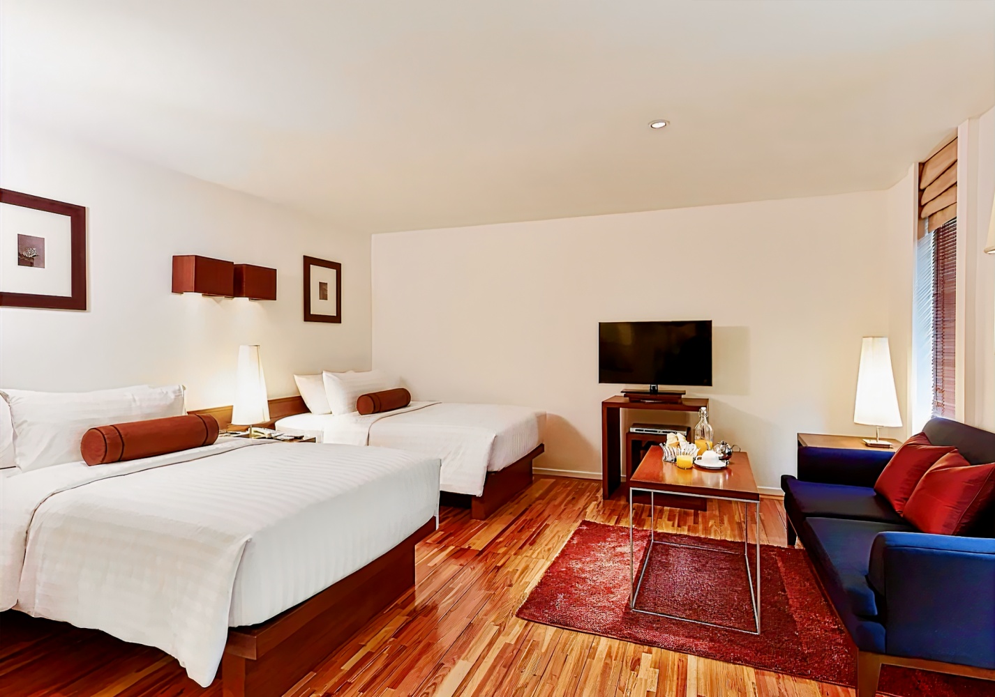 Triple Two Silom Bangkok twin room — two beds, sofa, warm hardwood floors, flat-screen TV