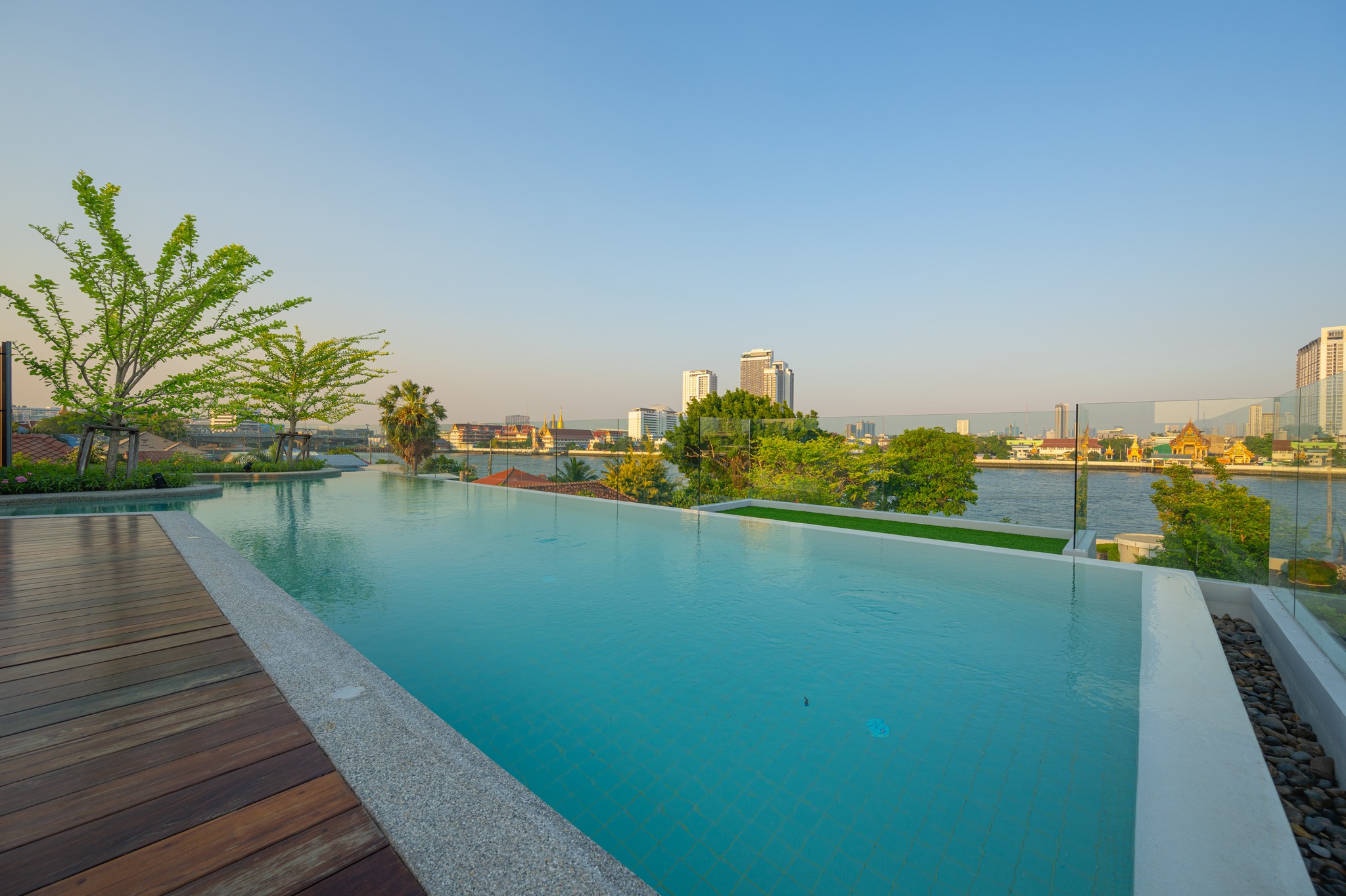 The lush riverside garden and outdoor seating area at WE Hotel Riverfront Bangkok