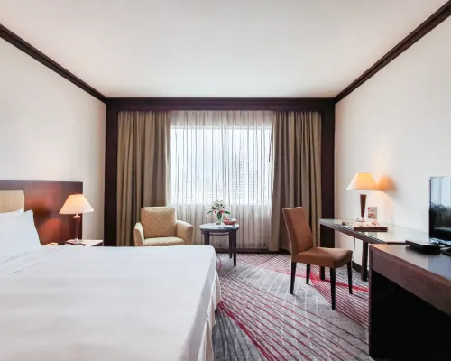 ห้องพักของ Zenith Sukhumvit Hotel โทนอบอุ่น ผ้าปูขาว เฟอร์นิเจอร์สีไม้