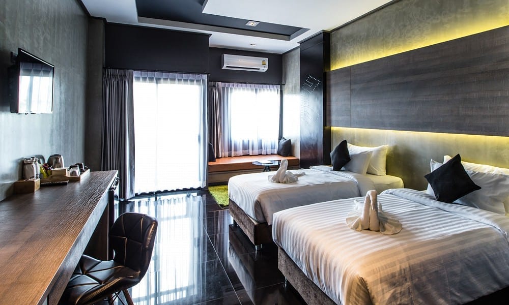 ห้องพักของ Cresco Hotel Buriram โทนเข้มสไตล์ลอฟต์ เตียงคู่และโต๊ะทำงานริมหน้าต่าง