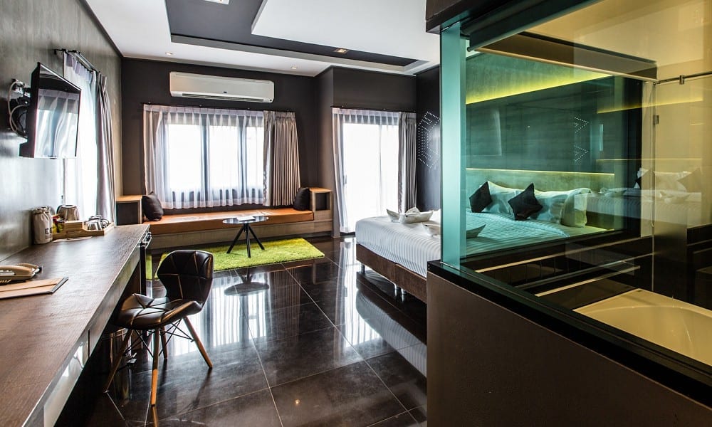 ห้องสวีทของ Cresco Hotel Buriram พร้อมห้องน้ำผนังกระจกใสและมุมนั่งเล่นพรมเขียว