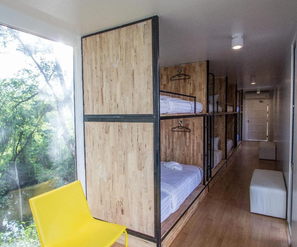 ห้องดอร์มเตียงสองชั้นภายในตู้คอนเทนเนอร์ของ Ducati Bike Box Hostel ผนังไม้ มีหน้าต่างมองเห็นต้นไม้