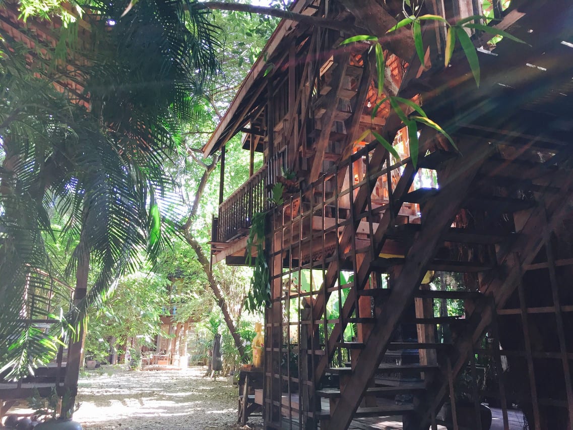 ห้องพักในเรือนไม้ตกแต่งด้วยไม้สักเก่าและผ้าทอท้องถิ่น เตียงคลุมมุ้ง