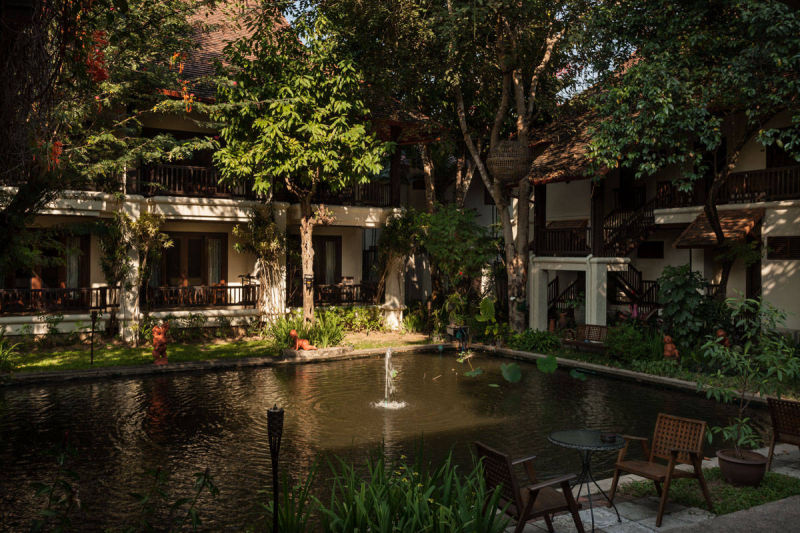 สวนกลางของ Lanna Dusita Riverside Boutique Resort มีสระน้ำพุล้อมด้วยอาคารไม้สักสไตล์ลานนา