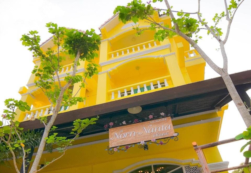 ห้องพักของ Norn-Nanta House ผนังสีสดใส มีแอร์ โต๊ะทำงาน และมุมนั่งเล่น
