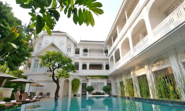 สระว่ายน้ำกลางแจ้งของ Ping Nakara ล้อมรอบด้วยอาคารโคโลเนียลสีขาวและต้นไม้เขียว
