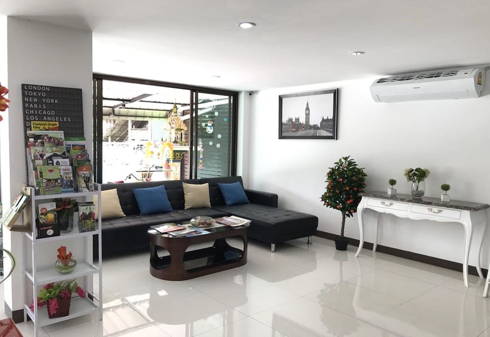 มุมนั่งเล่นส่วนกลางของ Rinn Boutique House โซฟาผ้าและของตกแต่งโทนขาวสไตล์ทันสมัย