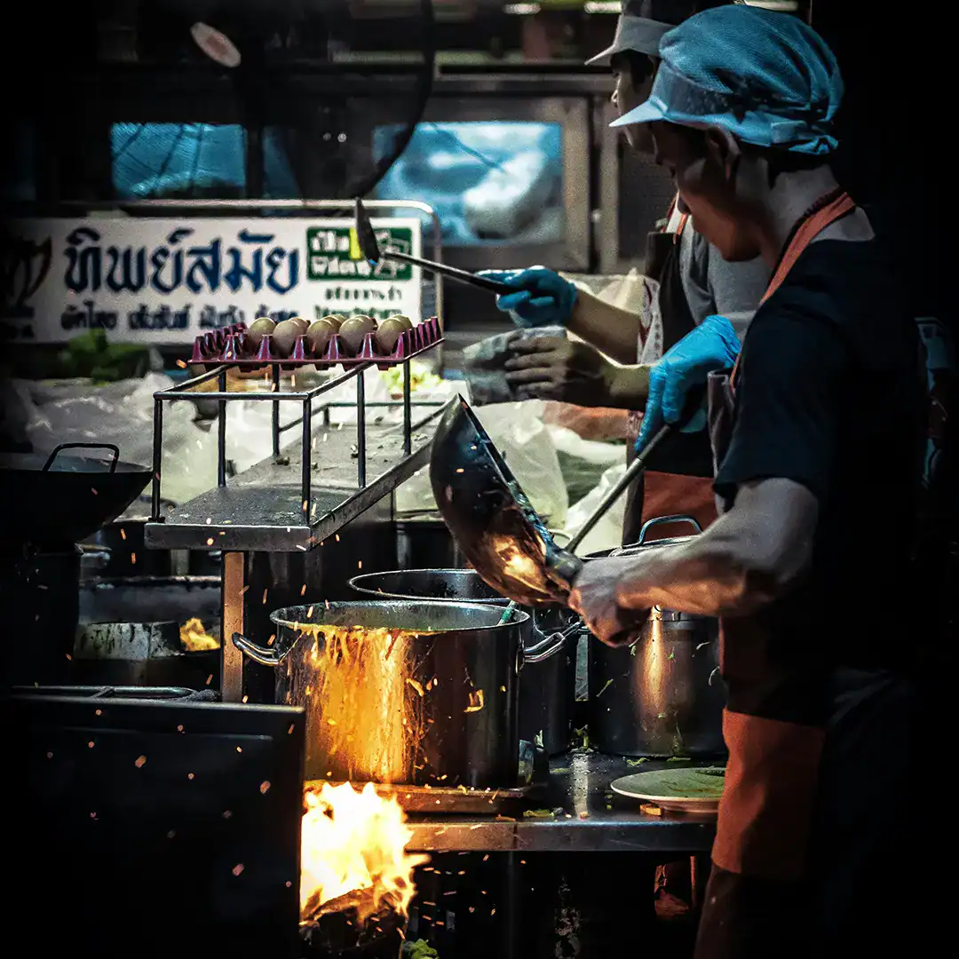พ่อครัวกำลังทำอาหารริมถนนในเชียงใหม่ บรรยากาศสตรีทฟู้ดใกล้เมืองเก่า