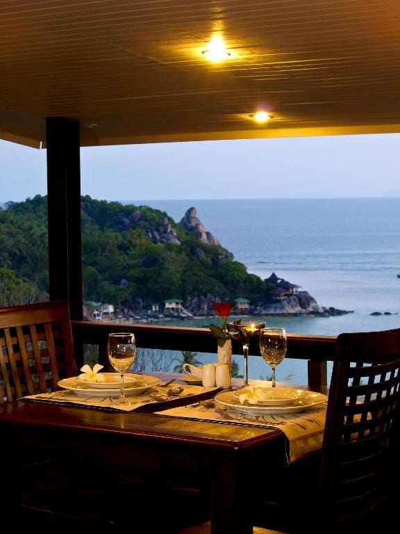 Warm-toned wooden room with a bed and a sea-view balcony at Chintakiri Resort Koh Tao