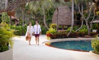 สระว่ายน้ำทรงลากูนของ Anantara Hua Hin ล้อมด้วยศาลามุงจากและสวนเขียว