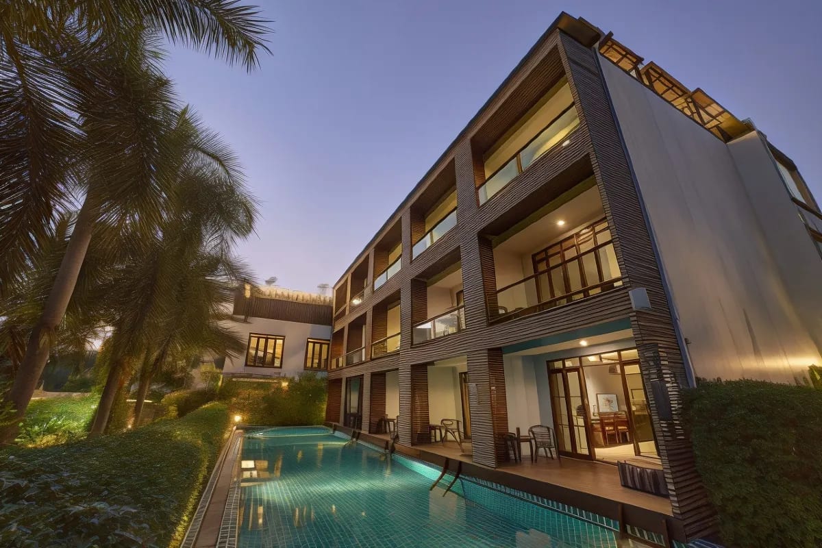 สระว่ายน้ำของ The Bihai Hua Hin ล้อมรอบด้วยอาคารห้องพักและสวนเขตร้อนโทนอบอุ่น