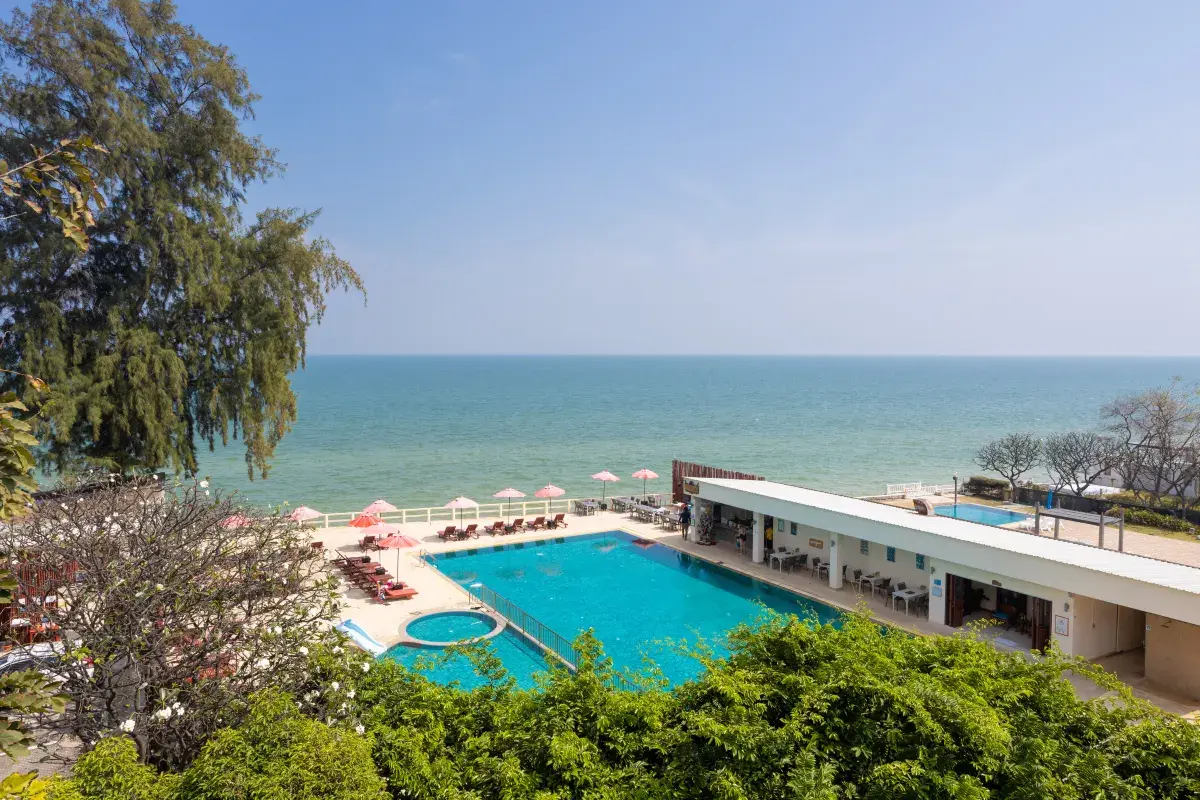 สระว่ายน้ำกลางแจ้งริมหาดของ Chom View Hotel หัวหิน มองเห็นทะเลเป็นฉากหลัง