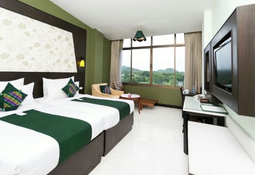 ห้องพักโทนอบอุ่นของ River Kwai Hotel กาญจนบุรี เตียงคู่และมุมนั่งเล่น