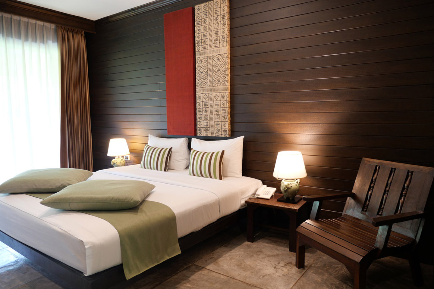 ห้อง Deluxe โทนไม้ของ Royal River Kwai Resort พร้อมระเบียงมองวิวสระและสวน