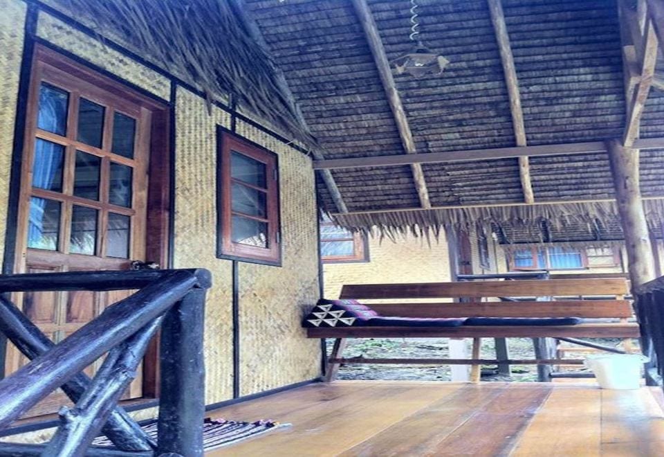 Wooden terrace in front of a Jungle Garden bungalow with a bamboo table and bench among green trees
