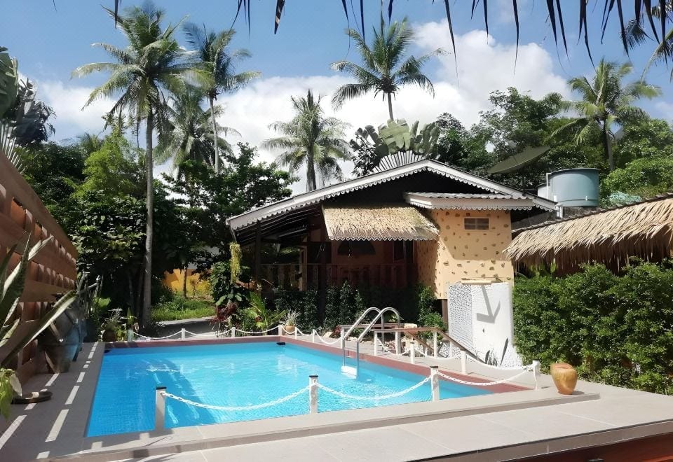Outdoor saltwater swimming pool at Macura Resort, Koh Chang, surrounded by a green garden and sun loungers