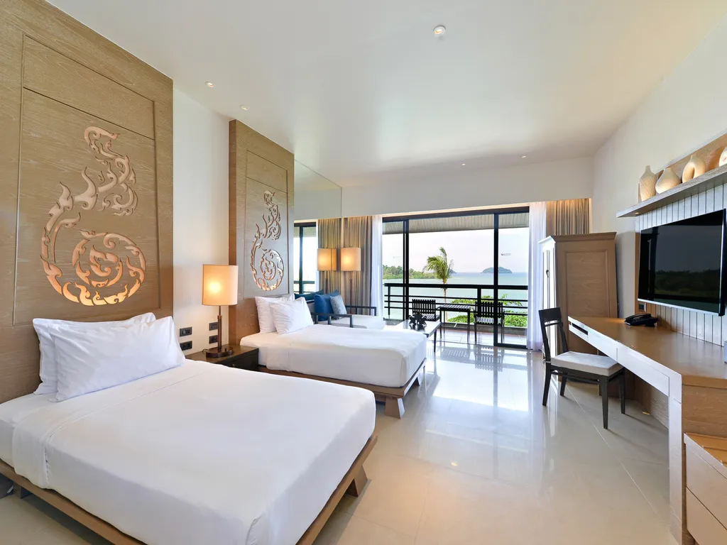 A beachfront deluxe room in warm tones with a wide sea-view balcony