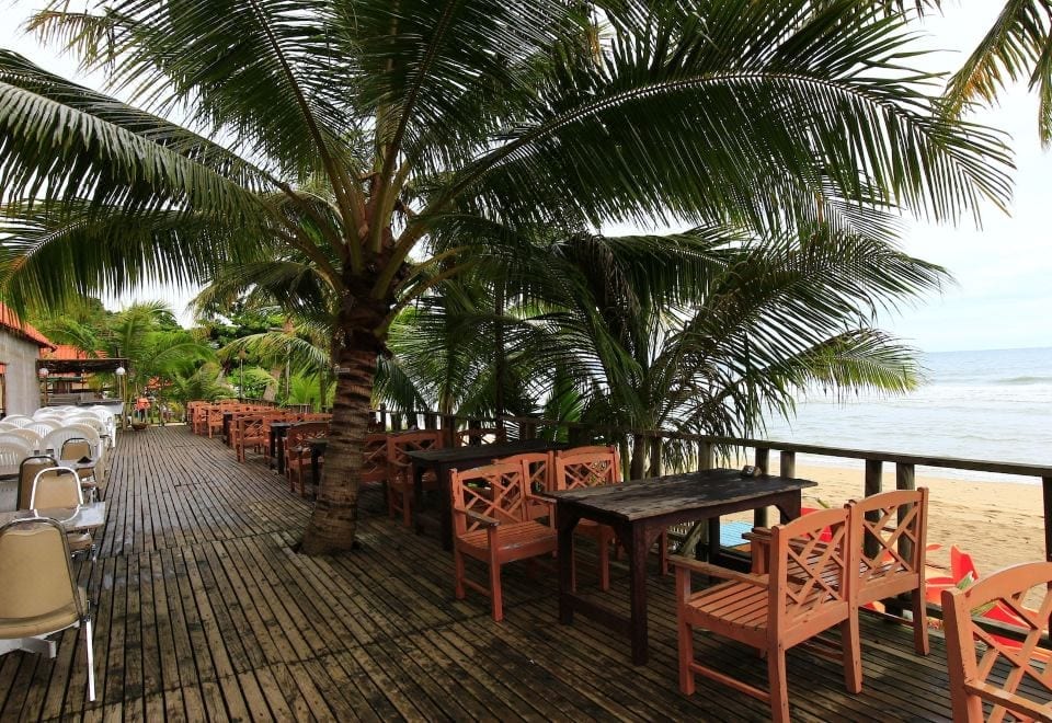 Beachfront restaurant terrace at White Sand Beach Resort under coconut palms, looking out over the white sand and the sea