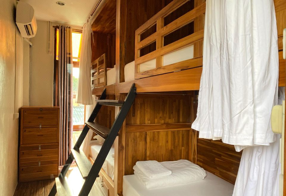 เตียงสองชั้นในห้องดอร์มของ Bloom Hostel มีม่านส่วนตัวและบันไดขึ้นเตียง