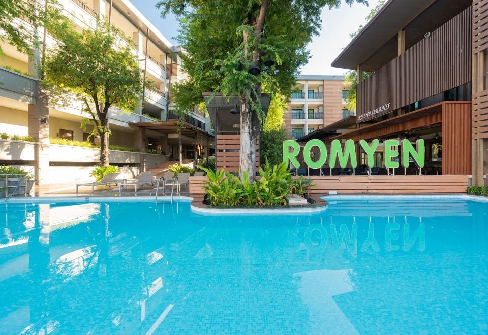 สระว่ายน้ำกลางแจ้งของ Romyen Garden Place พร้อมเตียงอาบแดดในบรรยากาศสวน
