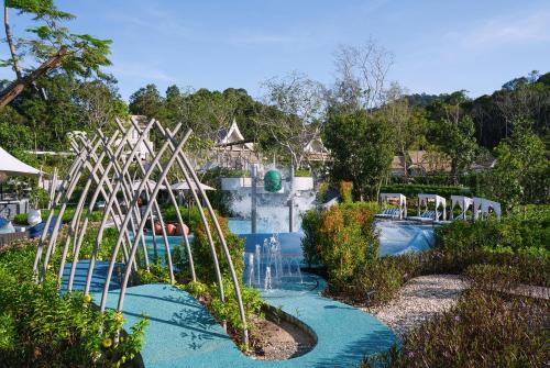 Banyan Tree Krabi's water garden and pool set among bamboo sculptures against a forest-and-mountain backdrop