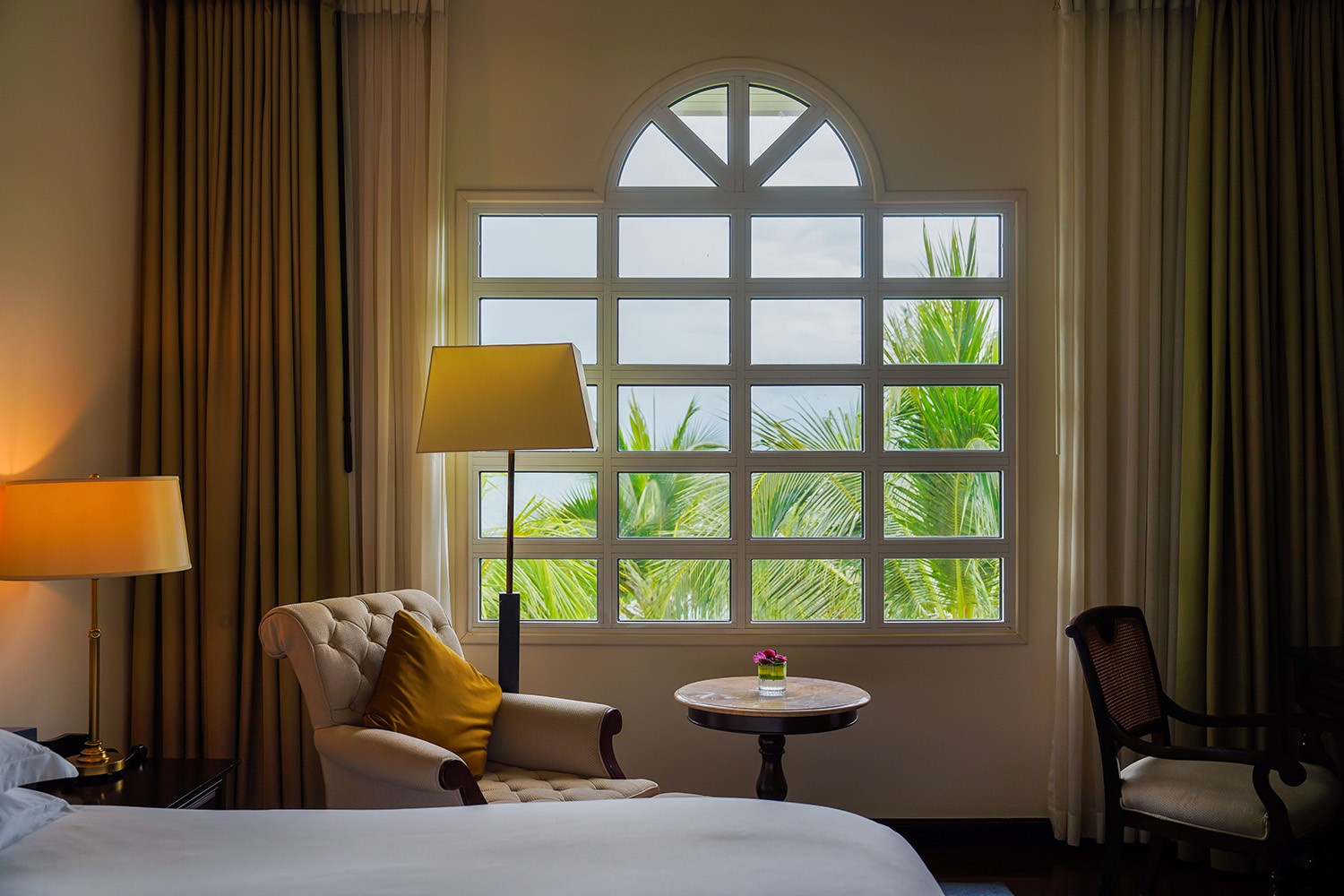 A colonial-style room at Sofitel Krabi Phokeethra with teakwood floors and an arched window onto palm gardens