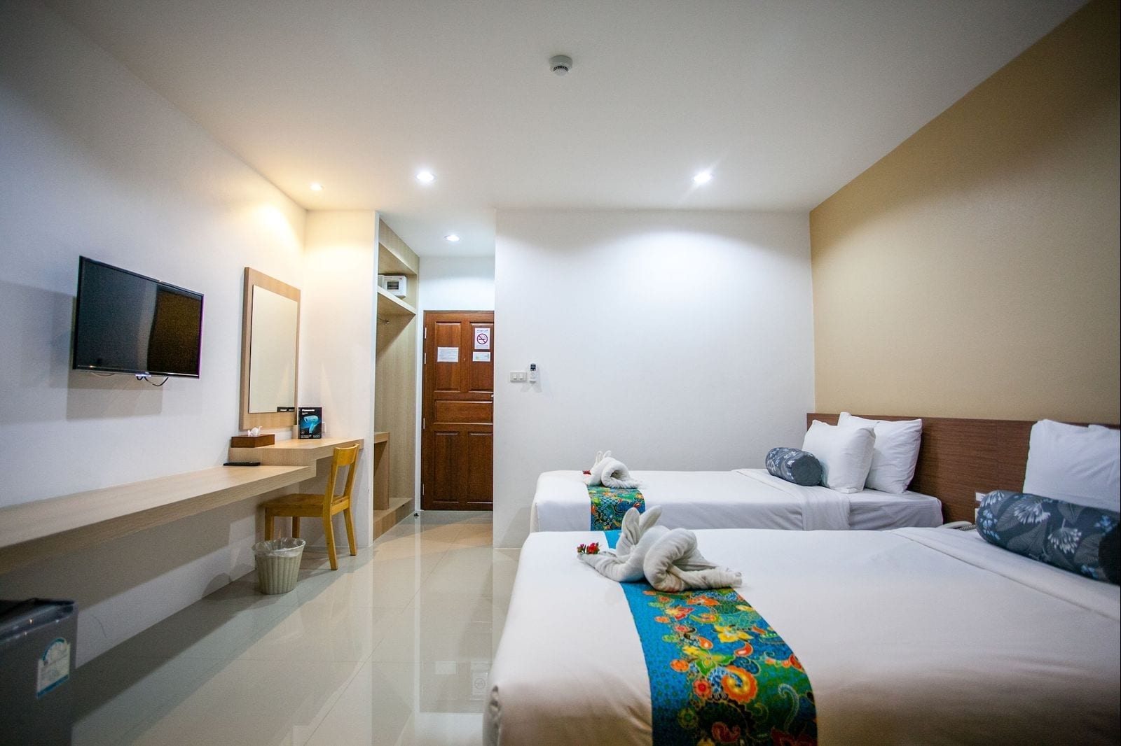 ห้องพักของ Wanarom Residence Hotel กระบี่ ตกแต่งโทนสว่างสะอาด มีเตียงคู่ ทีวีจอแบน โต๊ะทำงาน และพื้นกระเบื้องเงา