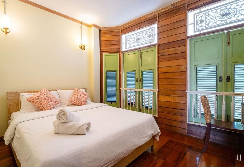 ห้องพักเรือนไม้ของ Muiphang Guesthouse พื้นไม้สักขัดเงา บานประตูหน้าต่างไม้ฉลุสีเขียวอ่อน เตียงคิงไซส์