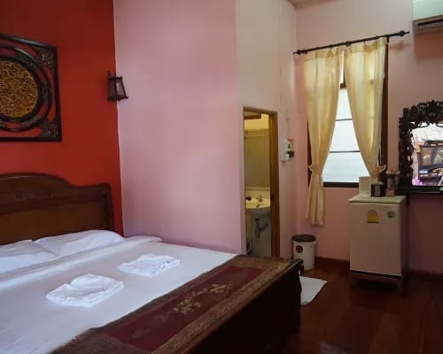 ห้องพักโทนไม้และส้มอุ่นสไตล์ไทยโบราณของ The Old Chiangkhan Boutique Hotel พร้อมเตียงคิงและระเบียง